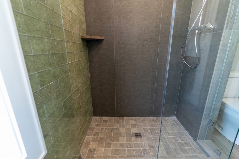 walk-in-shower-with-custom-tile-floor-walls-and-hinged-glass-door