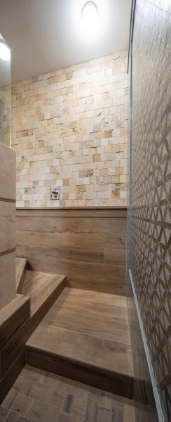 wooden-stairs-leading-to-powder-bathroom-with-custom-tiled-walls