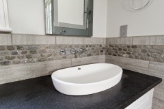 custom-tile-bathroom-with-white-oval-sink-and-dark-countertop