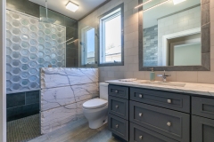walk-in-shower-with-blue-tile-next-to-toilet-and-single-sink